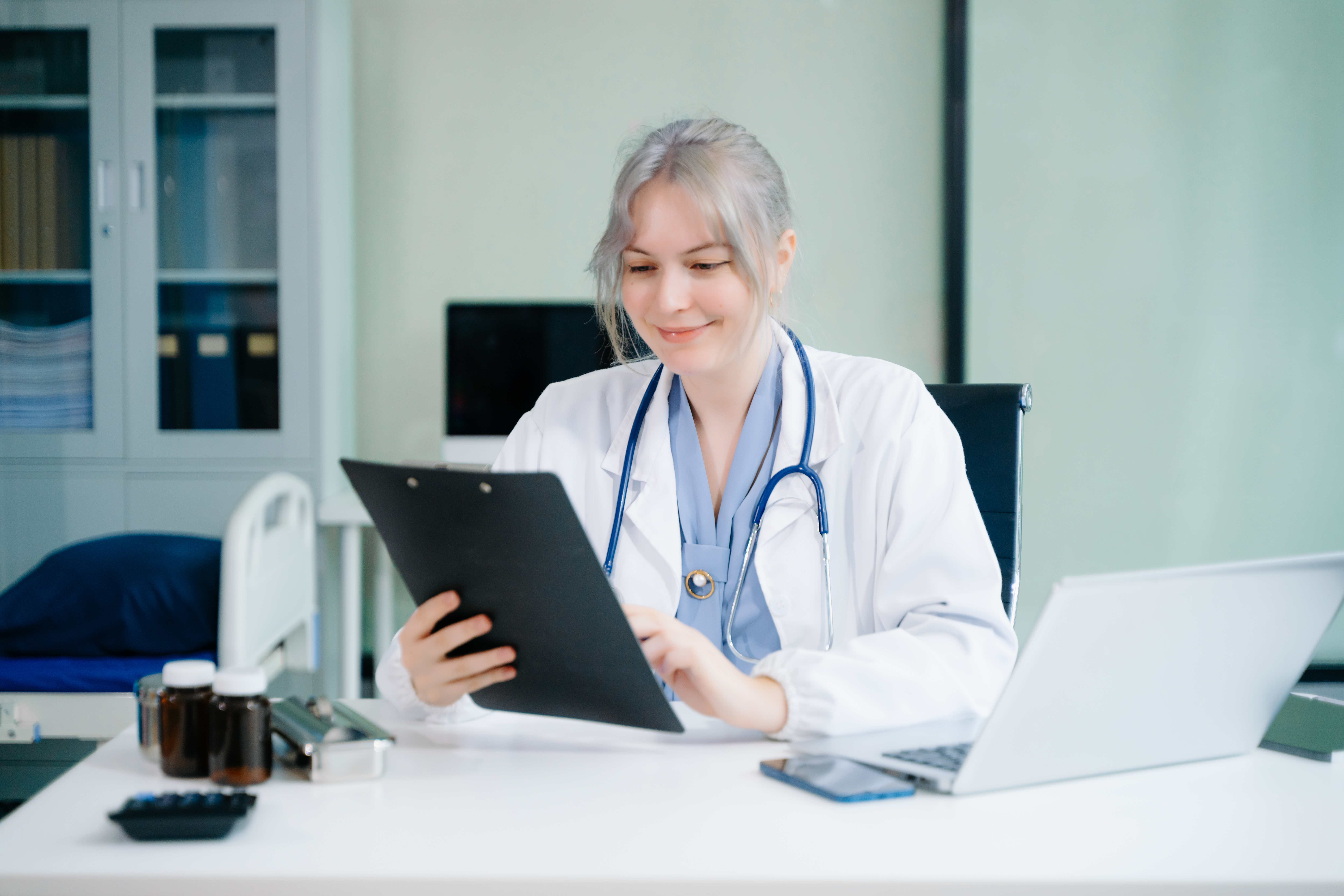 Clinician reviewing clinical documentation on a laptop and tablet at a workstation